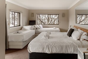 Une chambre avec deux lits, une télévision et de grandes fenêtres donnant sur la forêt.