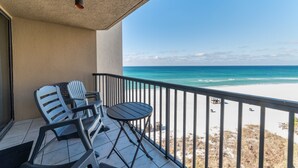 Ein Balkon mit Blick auf den Strand, einem Tisch und zwei Stühlen.