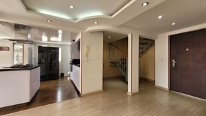 Une cuisine moderne dotée d’un îlot central, d’un escalier menant à un niveau supérieur et d’une porte en bois foncé.