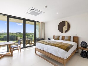 A modern hotel room with a large bed, a dining table, and a view of the city. - B303 (Cupecoy)