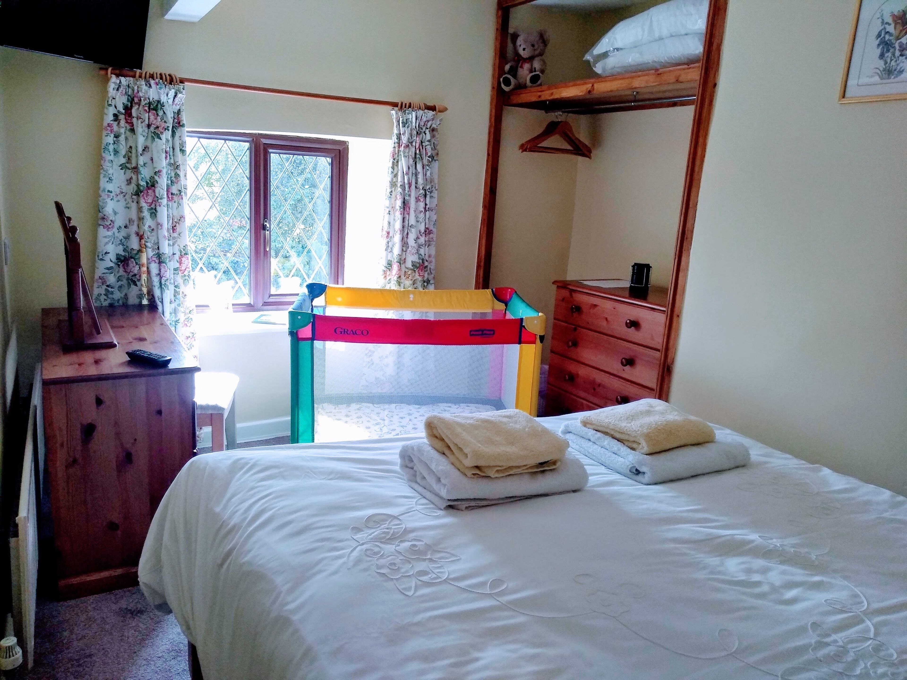 A bedroom with a bunk bed, a desk with a chair, a dresser, and a window with curtains.