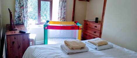 A bedroom with a bunk bed, a desk with a chair, a dresser, and a window with curtains.