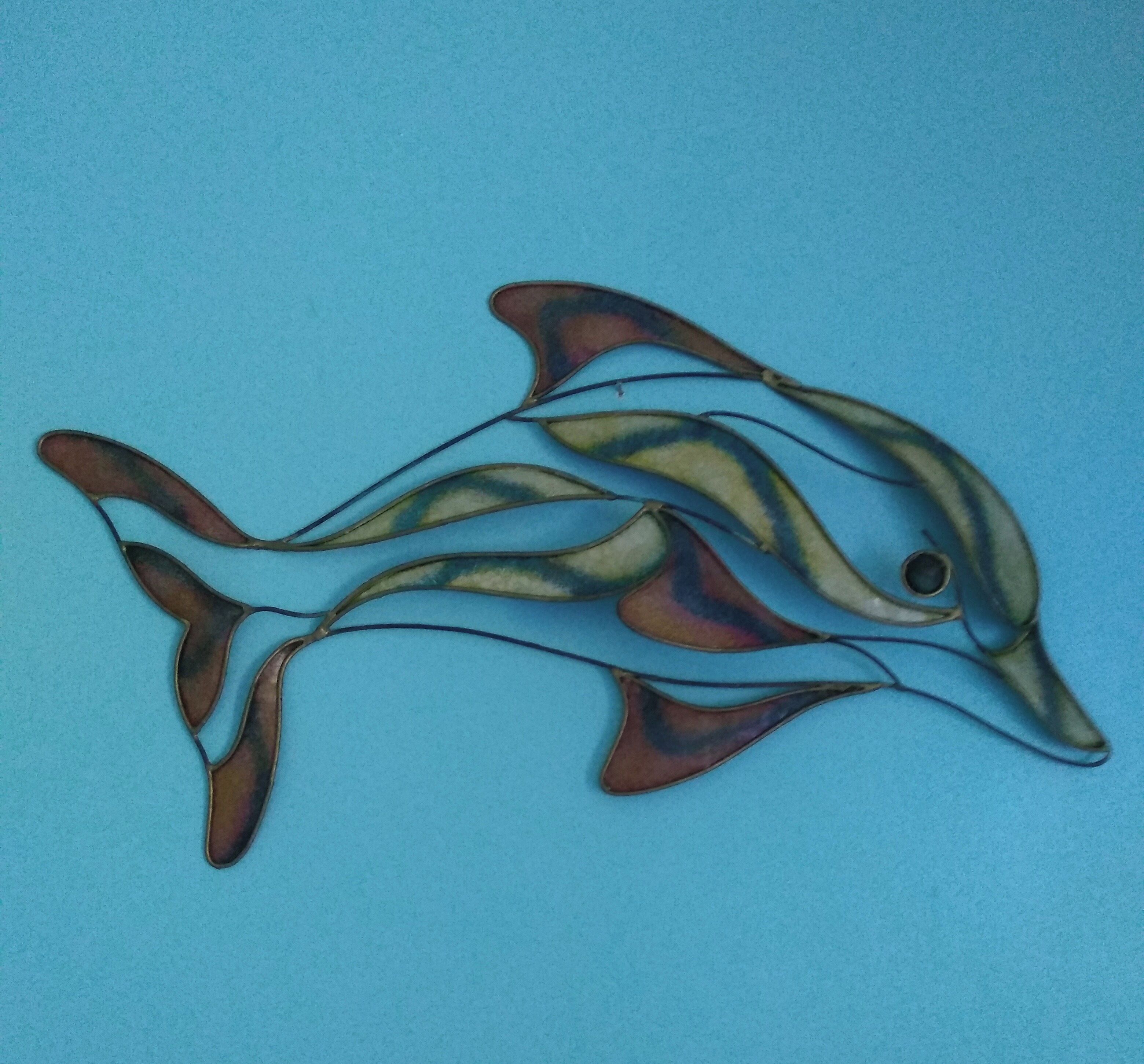 Una escultura de delfín sobre un fondo azul.