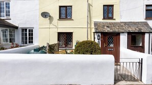 Una casa de dos pisos con fachada blanca, una puerta marrón y una antena parabólica.