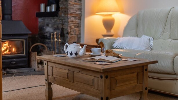 Una sala de estar acogedora con chimenea, una mesa de centro de madera, un sofá blanco y una lámpara.