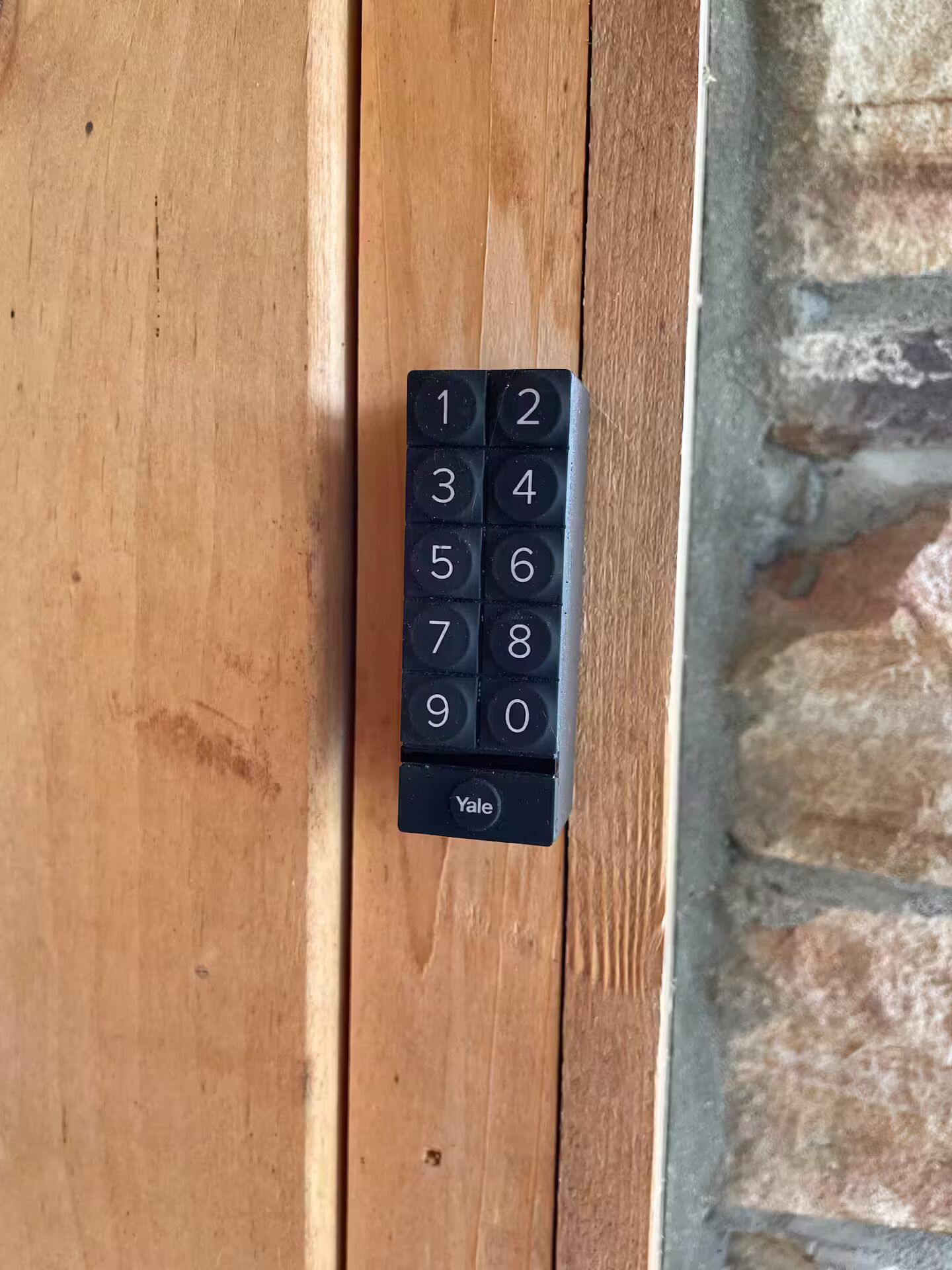 A Yale keypad lock mounted on a wooden door.