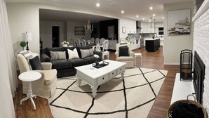 Een moderne woonkamer met een bank, salontafel en een eethoek op de achtergrond.