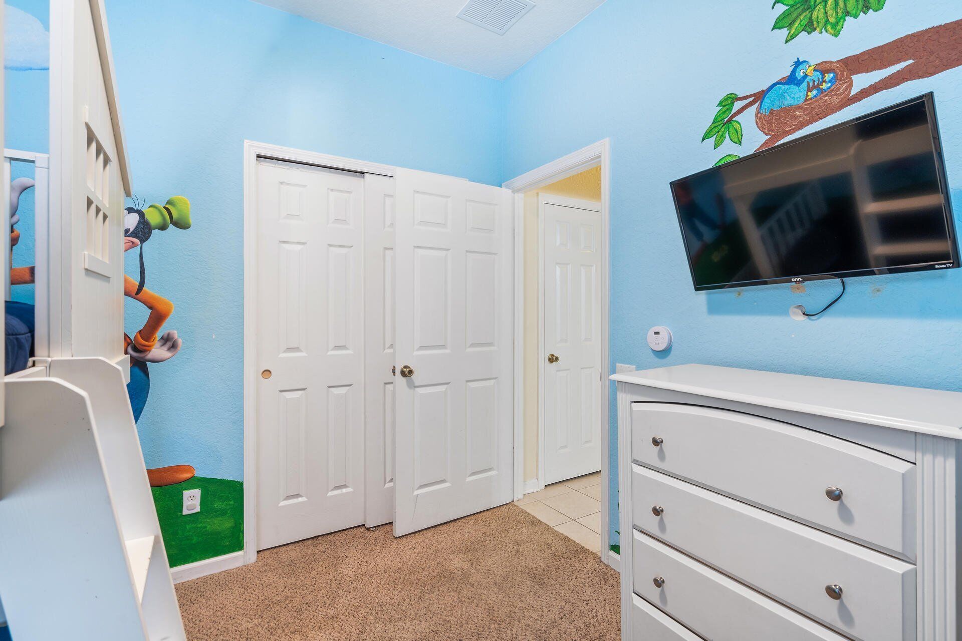 A child's room with a TV, a dresser, and a door.