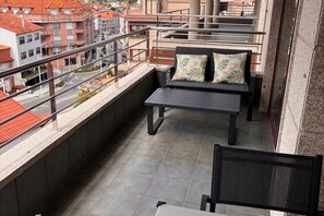 Un balcon avec un canapé et une table, une balustrade et une vue sur des immeubles aux toits rouges.