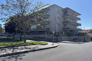 A multi-story residential building with a modern design, a speed limit sign, and a parking sign.