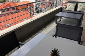 A rooftop terrace with a seating area, a table, and a potted plant.