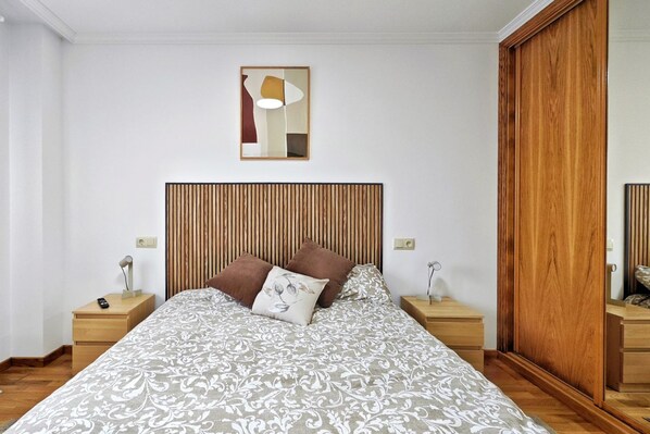 Un dormitorio con una cama, cabecera de madera, mesitas de noche y una mesilla.