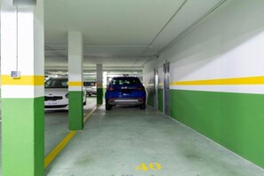 Un estacionamiento con paredes verdes y blancas, un coche azul aparcado a lo lejos y una línea amarilla en el suelo.