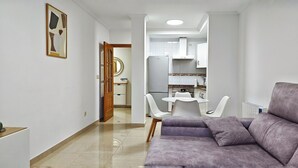 Una sala moderna con sofá y comedor, con mesa y sillas.