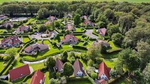 Een vogelperspectief van een woongebied met huizen, omgeven door goed onderhouden tuinen en bomen.