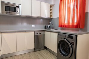 A compact kitchen with a microwave, dishwasher, and washing machine.