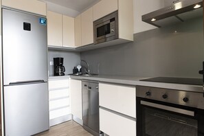 A modern kitchen with stainless steel appliances, including a refrigerator, microwave, and oven.