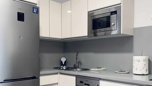 Een moderne keuken met roestvrijstalen apparatuur, waaronder een koelkast, magnetron en vaatwasser.
