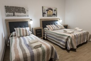 Una camera d'albergo con due letti, ognuno dotato di testiera, comodini e lampade.