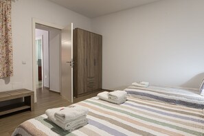 A bedroom with two beds, a wardrobe, and a bathroom visible through an open door.
