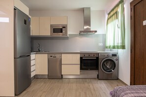 A compact kitchen with a refrigerator, microwave, dishwasher, oven, and washing machine.