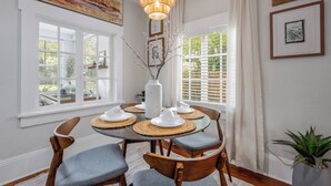 Un espace repas comprenant une table ronde, des chaises, un vase et un luminaire suspendu.