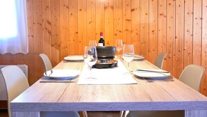 A wooden-paneled dining room with a table set for two, a bottle of wine, and two glasses.