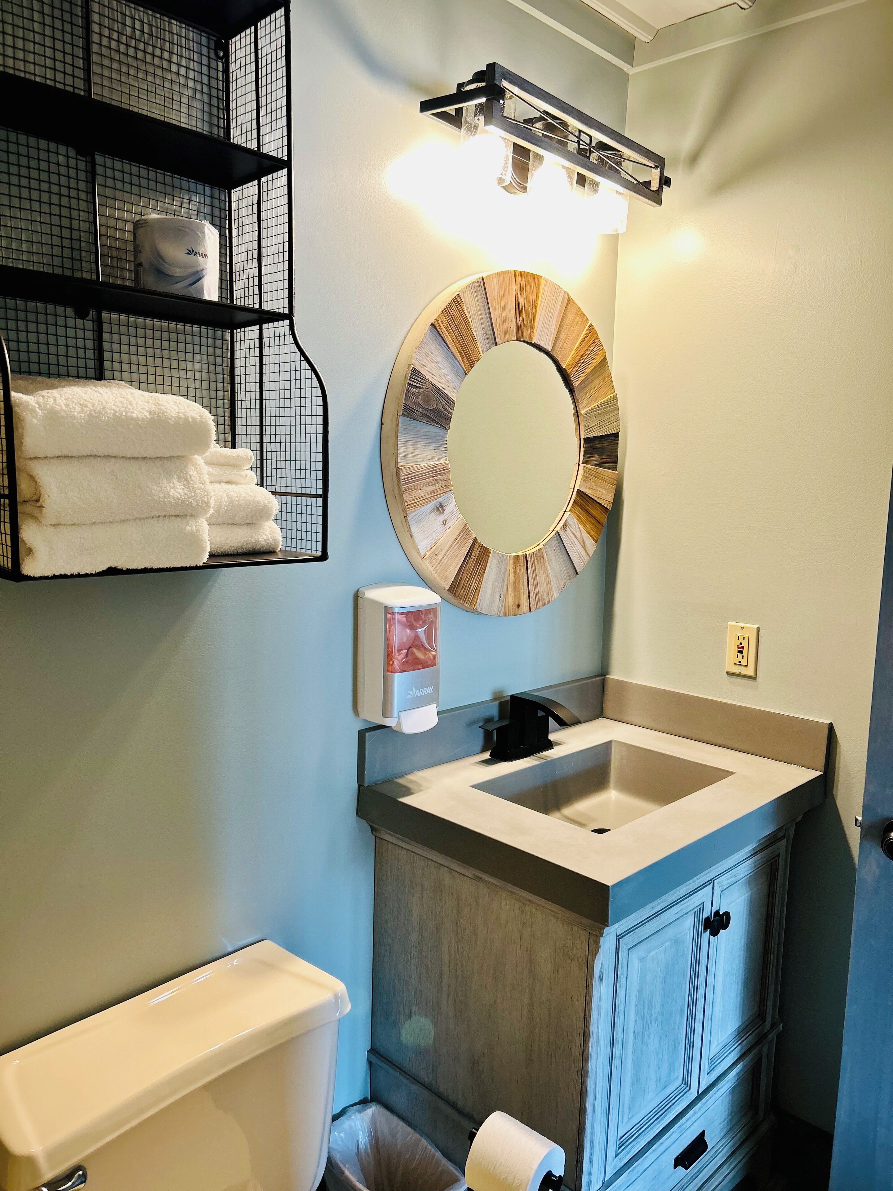 A bathroom with a sink, mirror, towel rack, and toilet.