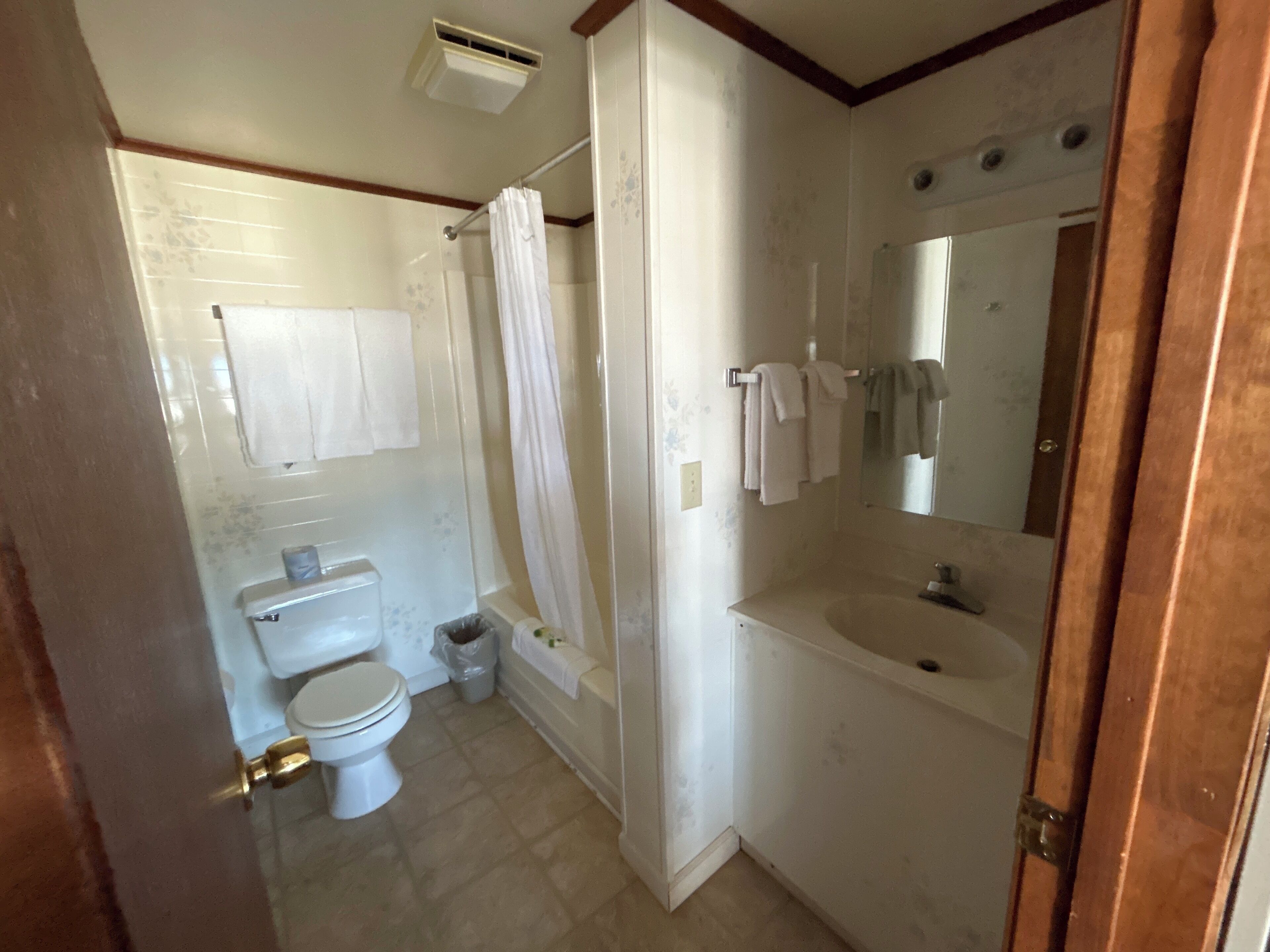 A bathroom with a toilet, shower, and sink.
