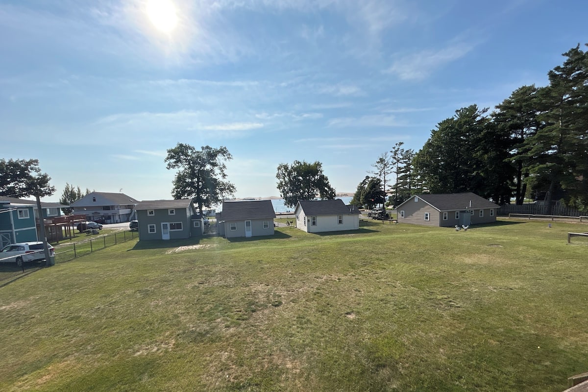 A residential area with houses, a grassy lawn, and trees.