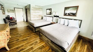 A hotel room with two beds, a wooden floor, a desk with a chair, and a mirror. - Silver Sands Hotel & Resort (Mears)