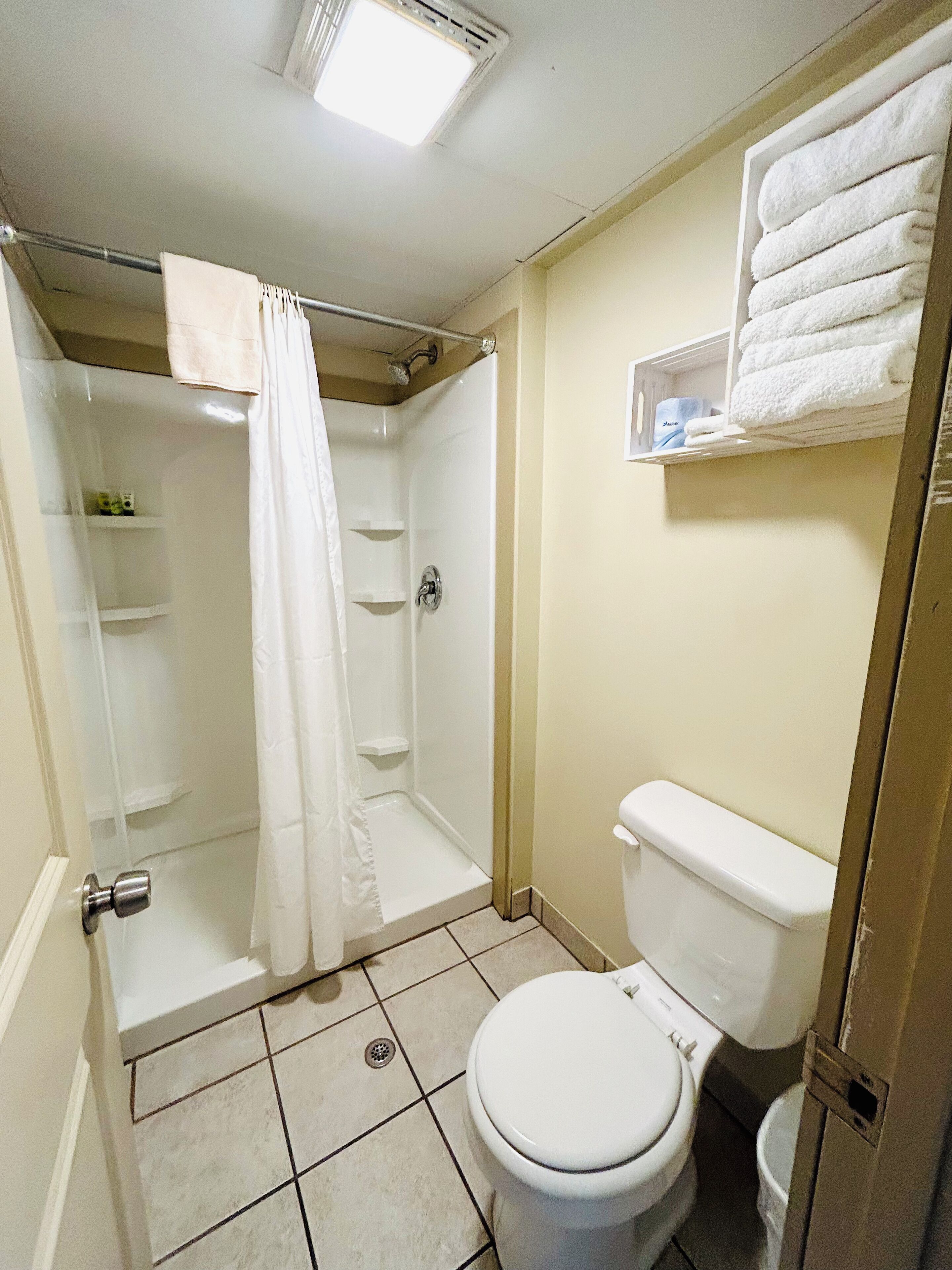 A bathroom with a shower, toilet, and a towel rack.