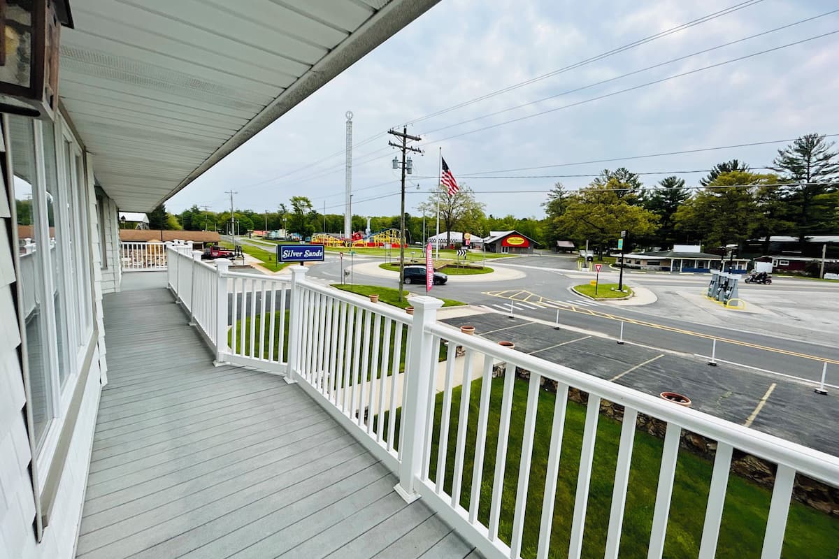 A balcony with a view of a street, a playground, and a gas station.