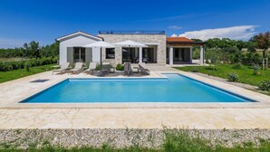 A modern house with a swimming pool, outdoor seating, and a stone facade.