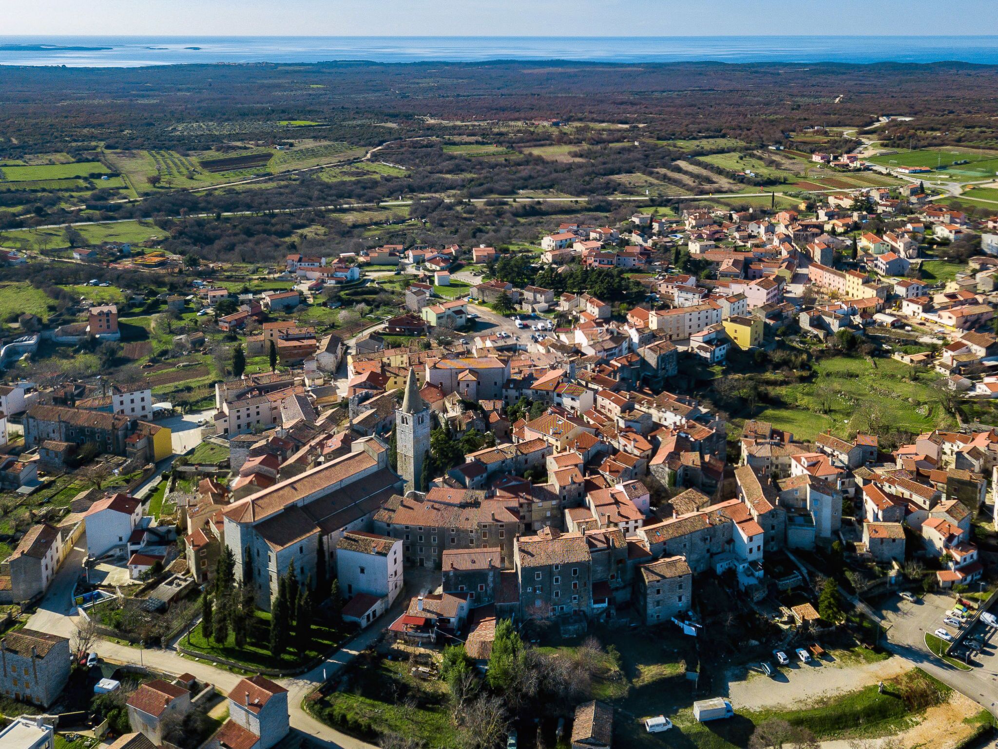 Vista aérea de un pueblo histórico con calles estrechas, arquitectura tradicional y una imponente torre de iglesia.