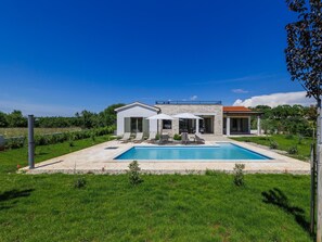 A modern house with a swimming pool, a covered patio, and a garden.