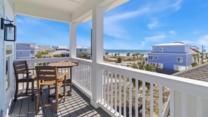 A covered outdoor area with a table and chairs, overlooking a beach and residential buildings. - New Listing! Luxury Beachside Townhouse GR8 Views! (Mexico Beach)