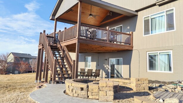 A two-story house with a covered patio, a fire pit, and a staircase leading to the upper level.