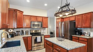 A modern kitchen with wooden cabinets, stainless steel appliances, granite countertops, and a central island.