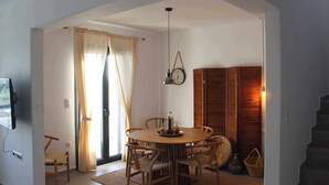 Un coin repas avec une table ronde, des chaises, une horloge et un escalier.