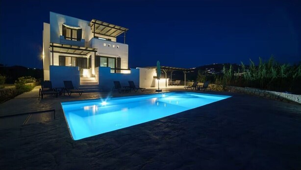 Une maison moderne avec une piscine, de nuit.