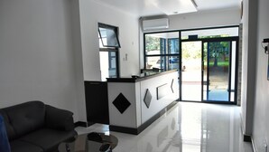 En moderne hotellobby med reception, sofa og sofabord i glas.
