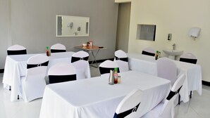 A conference room with tables and chairs, a small table with condiments, a mirror, and a sink. - Alexandrina's Corner Bed and Breakfast (Chipata)
