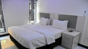 A modern bedroom with a large bed, bedside tables, and a window with curtains. - Alexandrina's Corner Bed and Breakfast (Chipata)