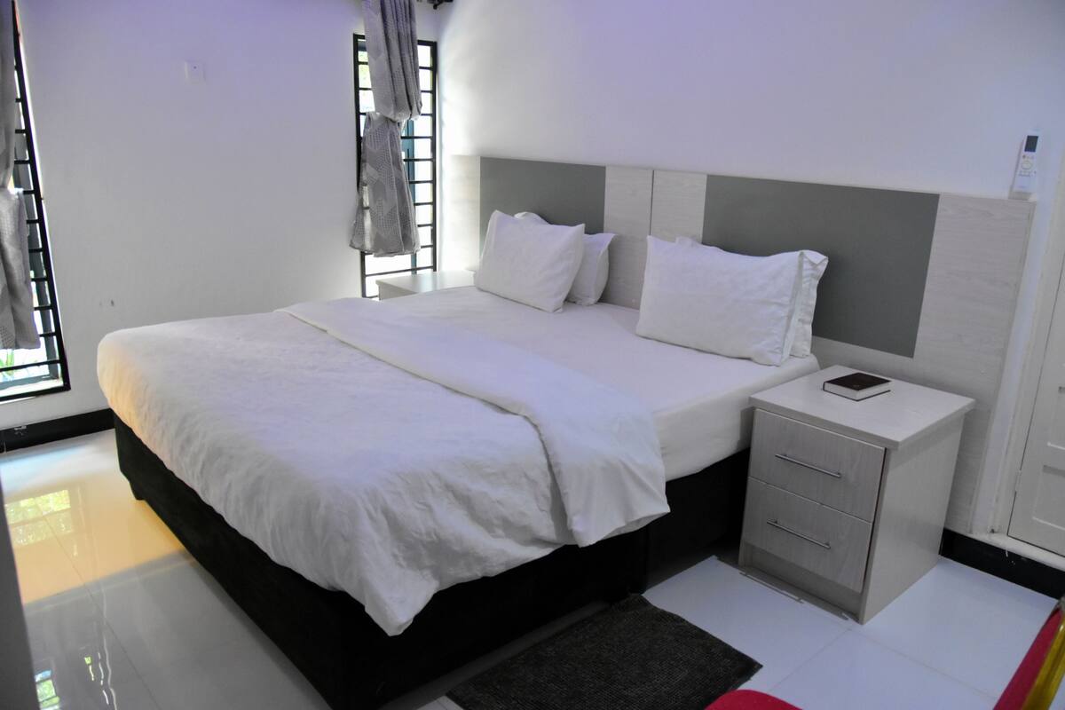 A modern bedroom with a large bed, bedside tables, and a window with curtains.
