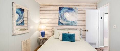 Una camera da letto con un letto grande, un comodino con una lampada e due quadri appesi al muro.