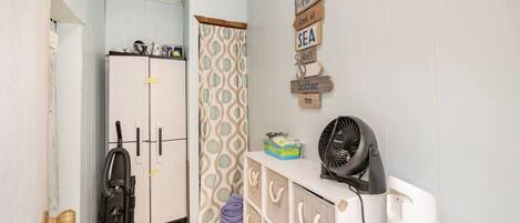 A compact room with a white radiator, a vacuum cleaner, a fan, and a laundry basket.