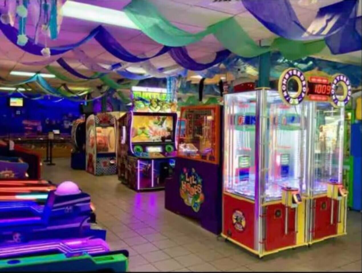 An arcade with various gaming machines, including claw games and racing games.