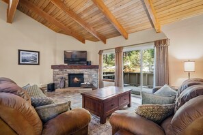 Una sala de estar acogedora con chimenea, sofás de cuero, una mesa de centro y un amplio ventanal con cortinas.