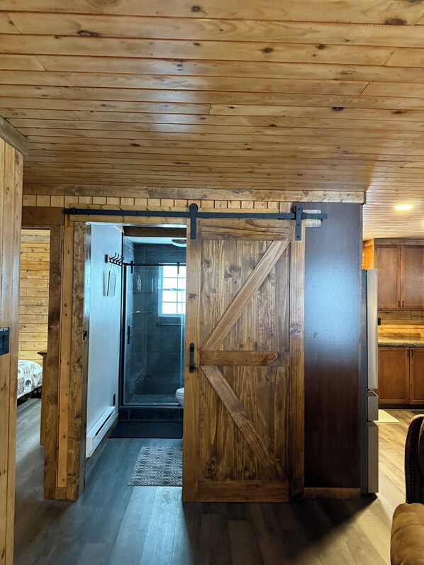 Un interior de madera con una puerta corredera estilo granero que da al baño.